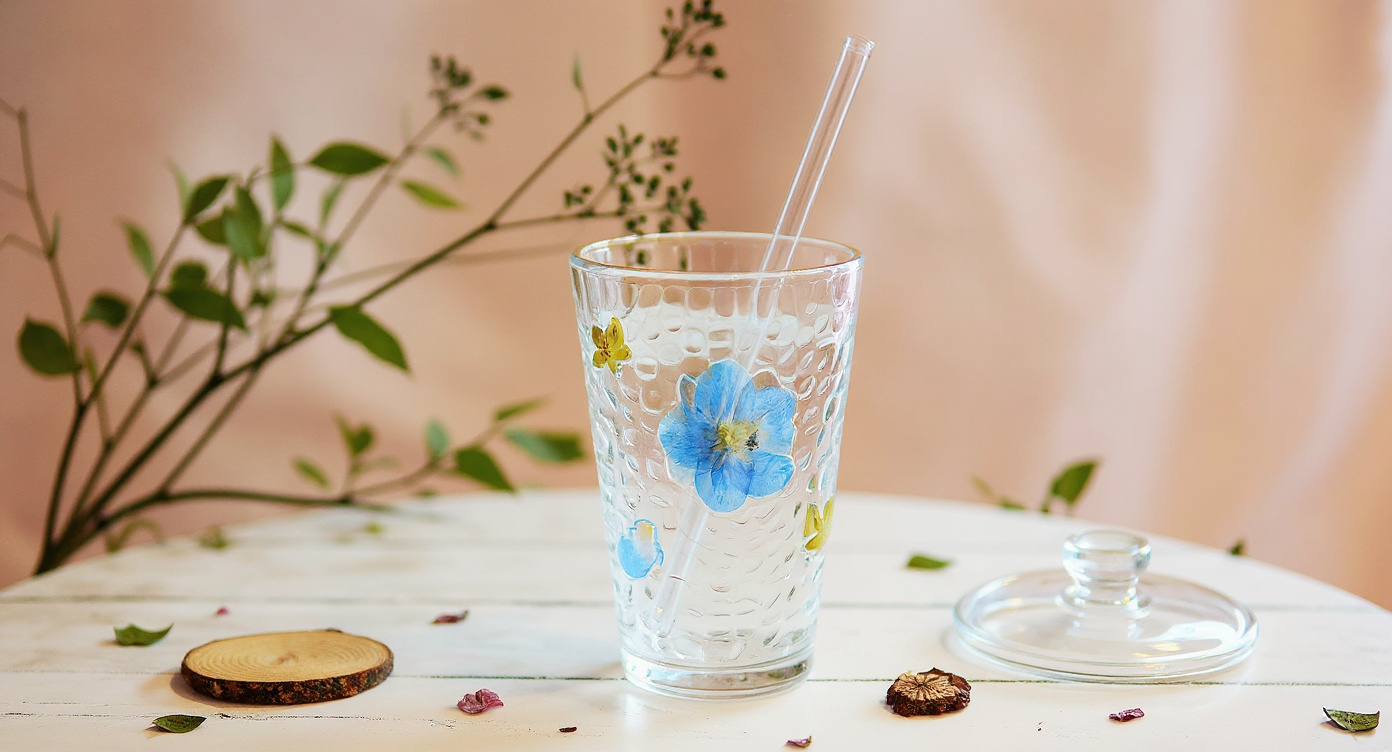 Handmade Real Flower Glass Cup with lid and straw on botanical journal flat lay