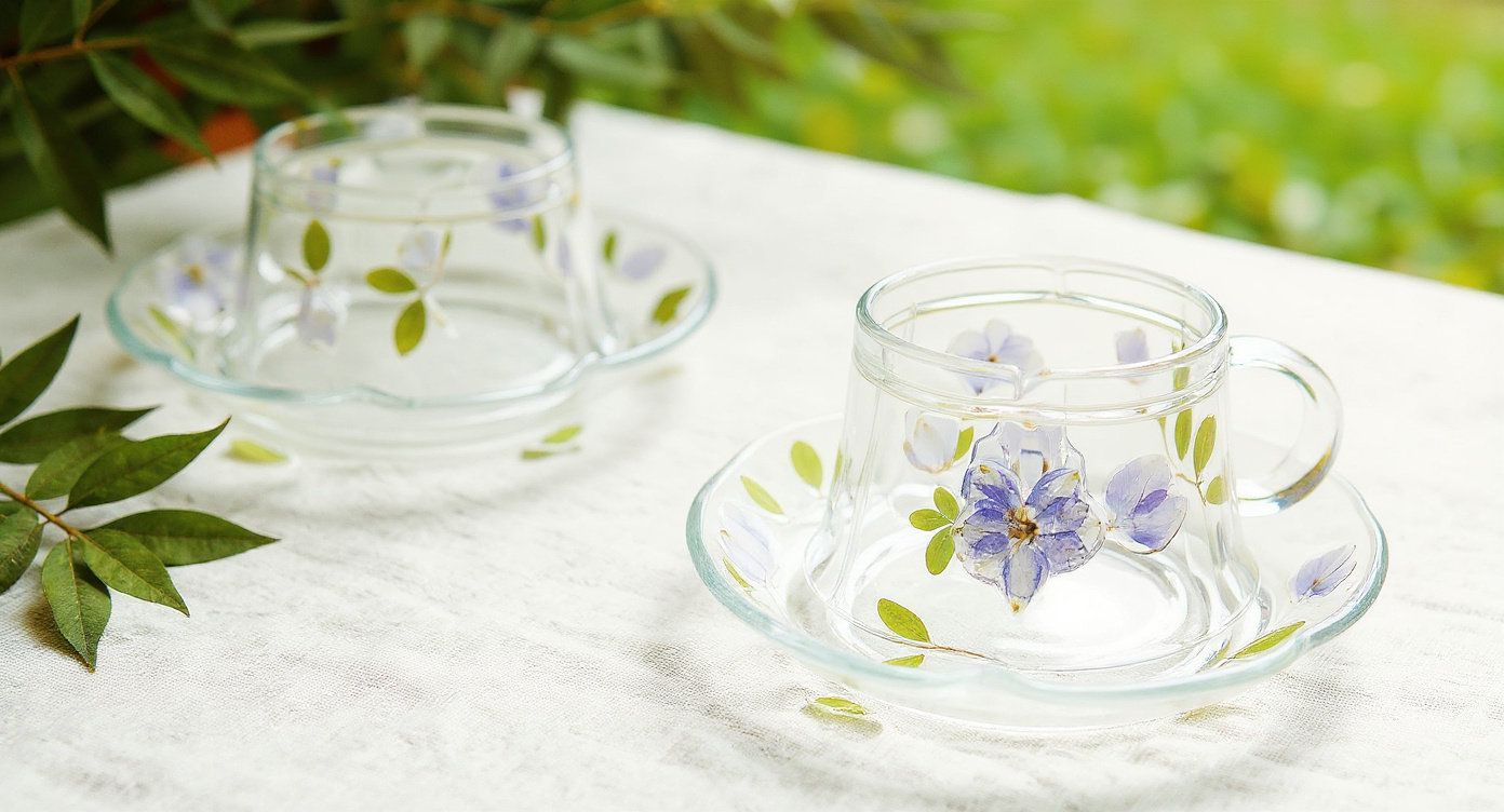 Overhead flat lay of handmade glass cup and saucer with dried flowers and spoon