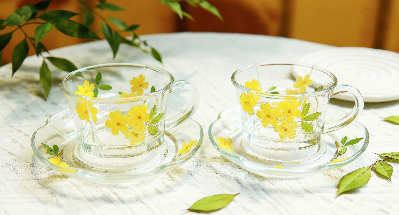 Handmade glass cup and saucer on shelf with ceramic honey jar and dried flowers