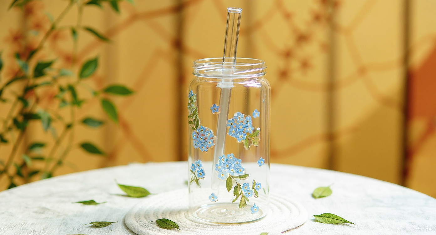 Handmade Glass Tumbler Real Preserved Flowers 600ml flat-lay with brass teaspoon and pampas grass.